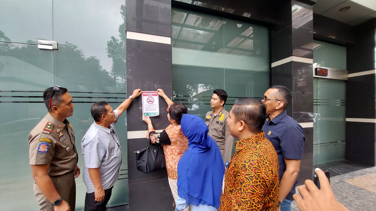 Lily memasang stiker kawasan tanpa rokok di Kampus Sari Mutiara. (Ist)